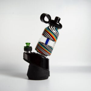 WIIDZ® Flask Alt puffco peak pro glass attachment installed on puffco peak, facing east. The glass shaped like a flask with a blue air inlet tube inside the bottle. red, orange, yellow, green, blue, black and white stripe swirl on the top and bottom.
