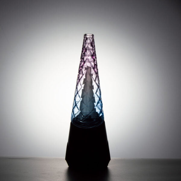 WIIDZ® Indiglow puffco peak pro glass attachment installed on puffco peak, facing south and lit from behind. The glass shaped like the original puffco peak pro glass but with diamond cut surface and iridescent color of purple and blue, just like the Puffco Peak Indiglow Glass.