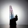 WIIDZ® Indiglow puffco peak pro glass attachment installed on puffco peak, facing west and lit from behind. The glass shaped like the original puffco peak pro glass but with diamond cut surface and iridescent color of purple and blue, just like the Puffco Peak Indiglow Glass.