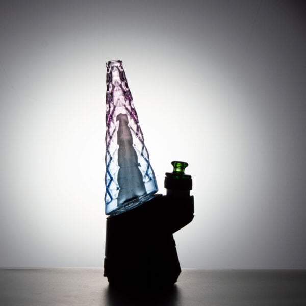WIIDZ® Indiglow puffco peak pro glass attachment installed on puffco peak, facing west and lit from behind. The glass shaped like the original puffco peak pro glass but with diamond cut surface and iridescent color of purple and blue, just like the Puffco Peak Indiglow Glass.