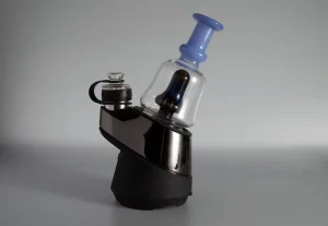 A close-up image of a Puffco Peak Pro glass attachment in a vibrant blue color, identified as WIIDZ Pico, installed on the device and positioned facing east. The glass features sleek lines and a glossy finish, capturing the light beautifully.